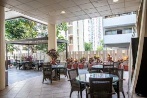 un patio al aire libre con mesas y sillas y un edificio en Aqua Aloha Surf Waikiki en Honolulu