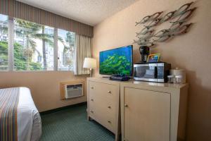 Habitación con cama y tocador con TV. en Aqua Aloha Surf Waikiki en Honolulu