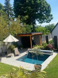 Griesheim-près-Molsheim的住宿－"Chez L" Maison individuelle 8 personnes - Jardin & Piscine Spa，一个带遮阳伞和椅子的游泳池