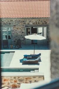 una mesa con sombrilla junto a una piscina en Sampatiki Suites - 4 Star Seaview Luxury Suites With Breakfast And Spa - Opened 2024 en Leonidion
