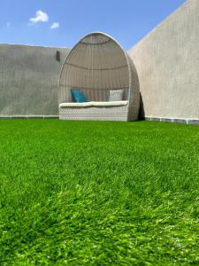 a green grass yard with a rattan bed on a building at Elite House in Taif
