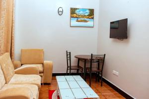 - un salon avec un canapé, une table et une télévision dans l'établissement Mesuma Hotel Dodoma, à Dodoma