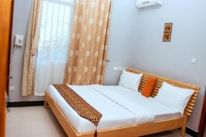 łóżko z pomarańczowymi i białymi poduszkami w pokoju w obiekcie Mesuma Hotel Dodoma w Dodomie