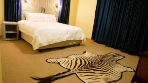 sypialnia z dywanem zebry na podłodze obok łóżka w obiekcie Vimbainashe Villas 