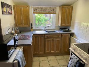 a kitchen with wooden cabinets and a sink and a window at Ivy Cottage in Salters lode