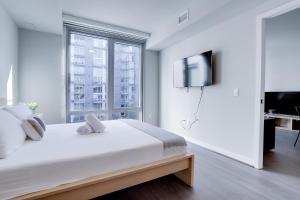 a white bedroom with a large bed and a tv at Experience Comfort and Style at Clarendon in Arlington