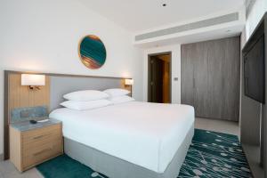 1 dormitorio con 1 cama blanca grande y TV en The First Collection at Jumeirah Village Circle, a Tribute Portfolio Hotel en Dubái