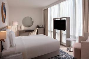 a white hotel room with a bed and a television at The First Collection at Jumeirah Village Circle, a Tribute Portfolio Hotel in Dubai