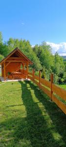einen Holzzaun mit einem Pavillon auf einem Feld in der Unterkunft Dolná chata u Bratríkov in Haligovce