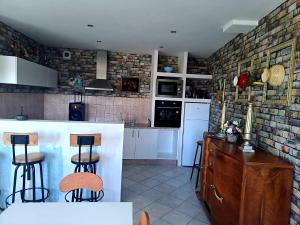a kitchen with a counter and two bar stools at La Mégritnière en campagne 3chambres in Mégrit