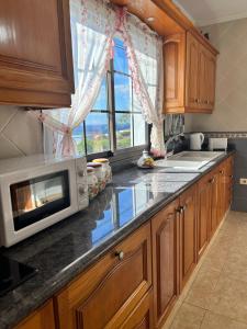 eine Küche mit Holzschränken, einer Mikrowelle und einem Fenster in der Unterkunft Casa Atilano Las Puntas La Frontera El Hierro in Las Puntas