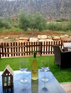 Una botella de vino y dos copas en una mesa. en Casa rural Rocío - Caminito del Rey, en Valle de Abdalajís