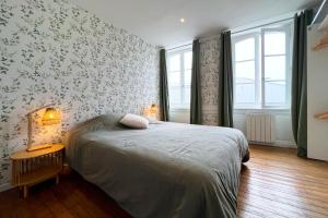 a bedroom with a bed with floral wallpaper at Appart de charme, 2 chambres en centre ville in Cherbourg en Cotentin
