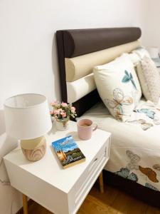 a bed with a table with a lamp and a book at Apartment Atria in Vrnjačka Banja