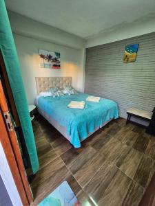 een slaapkamer met een bed met een blauwe deken bij GB Hostel IG in Puerto Iguazú