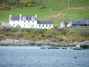 a large white house on the shore of a body of water at ISLE OF GIGHA FARM HOUSE in Ardminish