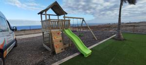 a playground with a green slide next to the ocean at Chalet Marpacos in Santa Cruz de Tenerife