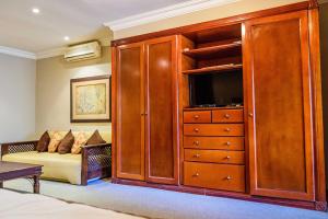 a large wooden entertainment center with a couch in a bedroom at RIETONDALE LODGE in Pretoria