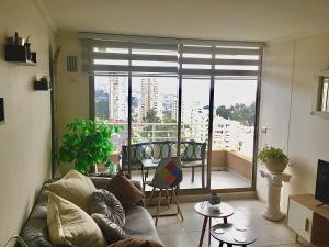 Departamento VIP vista al Mar y Ciudad في فالبارايسو: غرفة معيشة مع أريكة ونافذة كبيرة