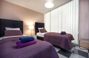 a bedroom with two beds with purple blankets and a window at Rooms & Apartments Banjac in Maribor