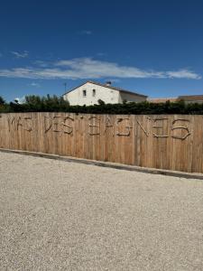 una recinzione di legno con graffiti su di esso con una casa sullo sfondo di Le Mas des Sagnes a Saintes-Maries-de-la-Mer