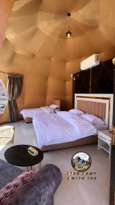 1 dormitorio con 1 cama grande y 1 mesa en STAR CAMP & WiTH TOR, en Wadi Rum