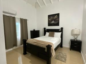 a bedroom with a bed with white sheets and a picture on the wall at Tropical Villa at Lakeside View in Salisbury