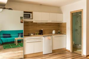 a kitchen with white cabinets and a living room at Apartmany Tereza & free parking in Bratislava