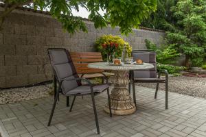 two chairs and a table and a bench with flowers at Apartmany Tereza & free parking in Bratislava