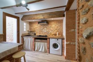 a kitchen with a washing machine and a brick wall at Ca la tía Luisa in Gayanes
