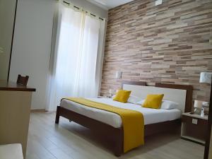 ein Schlafzimmer mit einem Bett mit gelben Kissen und einer Ziegelwand in der Unterkunft Domos La Corte Ghibellina in Iglesias