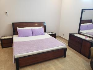 una camera da letto con letto, cuscini viola e specchio di lalic lavender a Islamabad