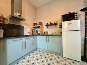 a kitchen with blue cabinets and a white refrigerator at La Chambre de Veyrines in Mérignac