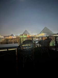 a table and chairs on a balcony with pyramids in the background at Nefertari pyramids inn in Cairo