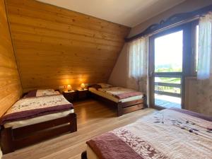 a bedroom with two beds and a large window at Jakubowy Domek in Cisna
