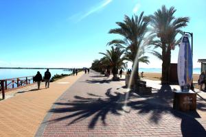 a sidewalk with palm trees and people walking on the beach at Casa estilo Riad Fez en Lo Pagan in San Pedro del Pinatar