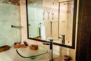 W łazience znajduje się szklana umywalka i lustro. w obiekcie Cozy Apartment in Maracaibo w Maracaibo