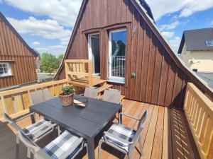 a wooden deck with a table and chairs on it at Ferienwohnungen Urlaubsglück in Kurort Gohrisch