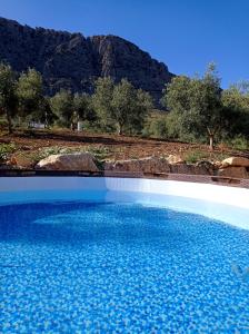 una piscina di acqua blu con una montagna sullo sfondo di Casa rural Rocío - Caminito del Rey a Valle de Abdalagís