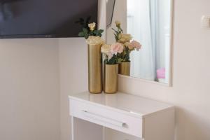 a white cabinet with two vases with flowers on it at Rooms Orion in Vodice