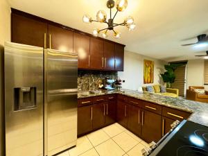 a kitchen with a stainless steel refrigerator and wooden cabinets at Ocean Luxe in Paradise - Le Paradis Royal in Rincon
