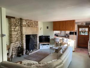 a living room with a couch and a stone fireplace at Cupcake Cottage: Quintessential Cotswold Cottage in Nailsworth