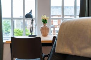 a desk with a vase with yellow flowers on it at Central, Stylish, & Modern Flat in Belfast