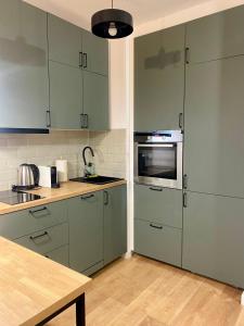 a kitchen with green cabinets and a wooden table at Chillout Airport Apartment KL33 - Free parking in Warsaw
