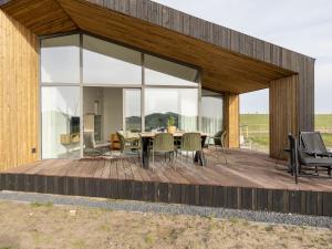 een glazen huis met een tafel en stoelen op een terras bij Lovely house in nature in Wissenkerke