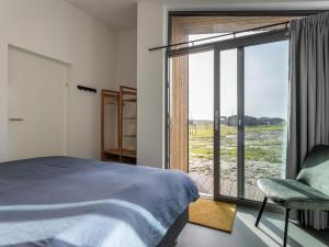 een slaapkamer met een bed en een glazen schuifdeur bij Lovely house in nature in Wissenkerke