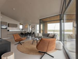 een woonkamer met een bank, stoelen en een tafel bij Charming holiday home with garden in Wissenkerke