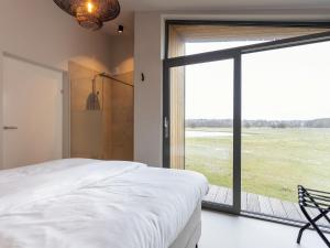 een slaapkamer met een bed en een groot raam bij Charming holiday home with garden in Wissenkerke