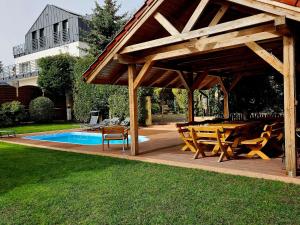 a wooden pavilion with a table and chairs next to a pool at holiday home, Kolczewo in Kołczewo