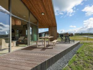 een houten terras met een tafel en stoelen op een huis bij Beautiful holiday home with garden in Wissenkerke